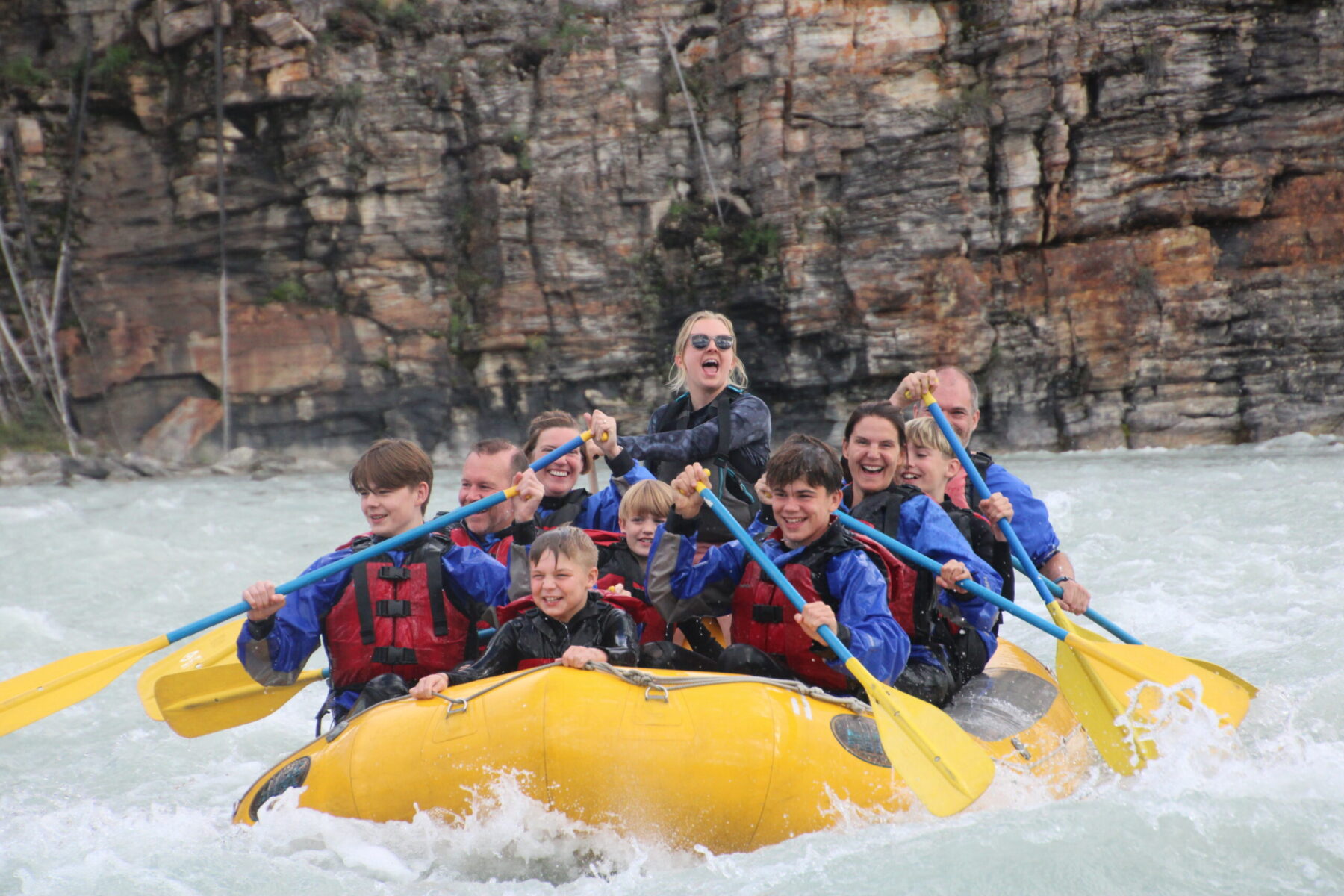 Whitewater rafters paddling through a mountain canyon on a glacially fed river